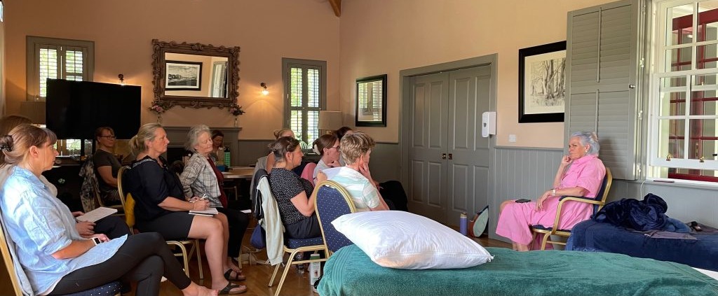 Clinical instructor demonstrating hands-on spinal assessment to a group of physiotherapists and osteopaths in a modern training room
